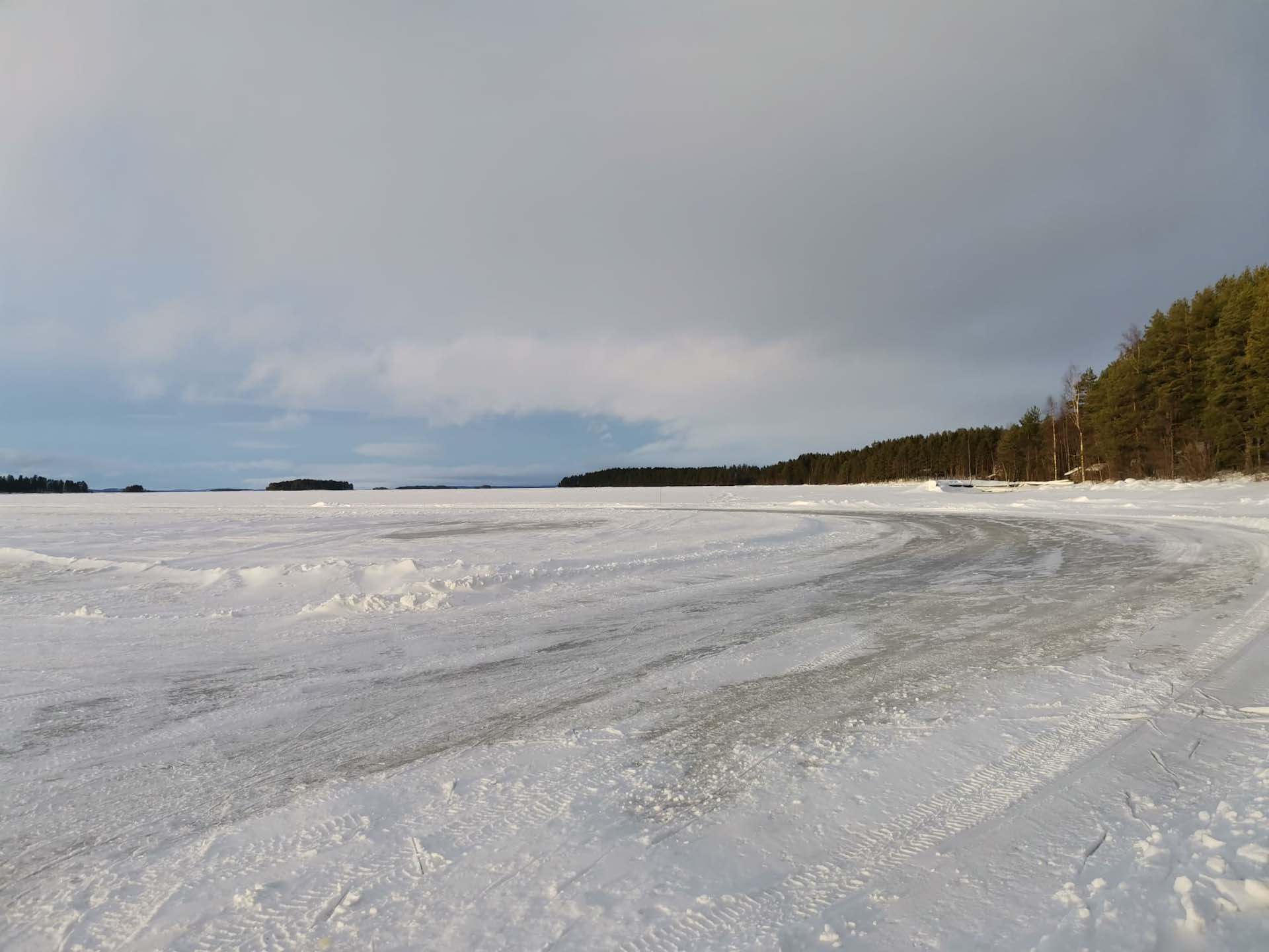 Järven jää rannalta kuvattuna. Jäätien alku, vasemmalla rannan metsää. Kauaempana saaria.