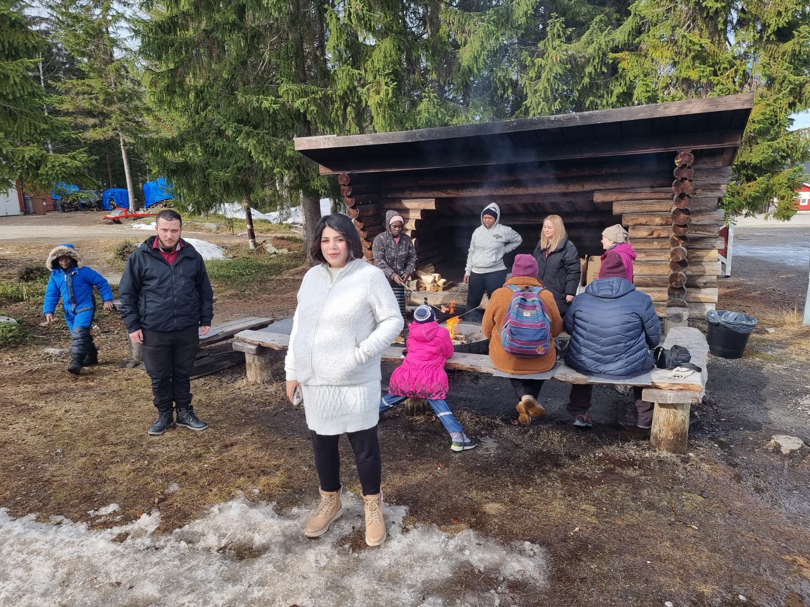 Ihmisiä kodalla nuotion äärellä.