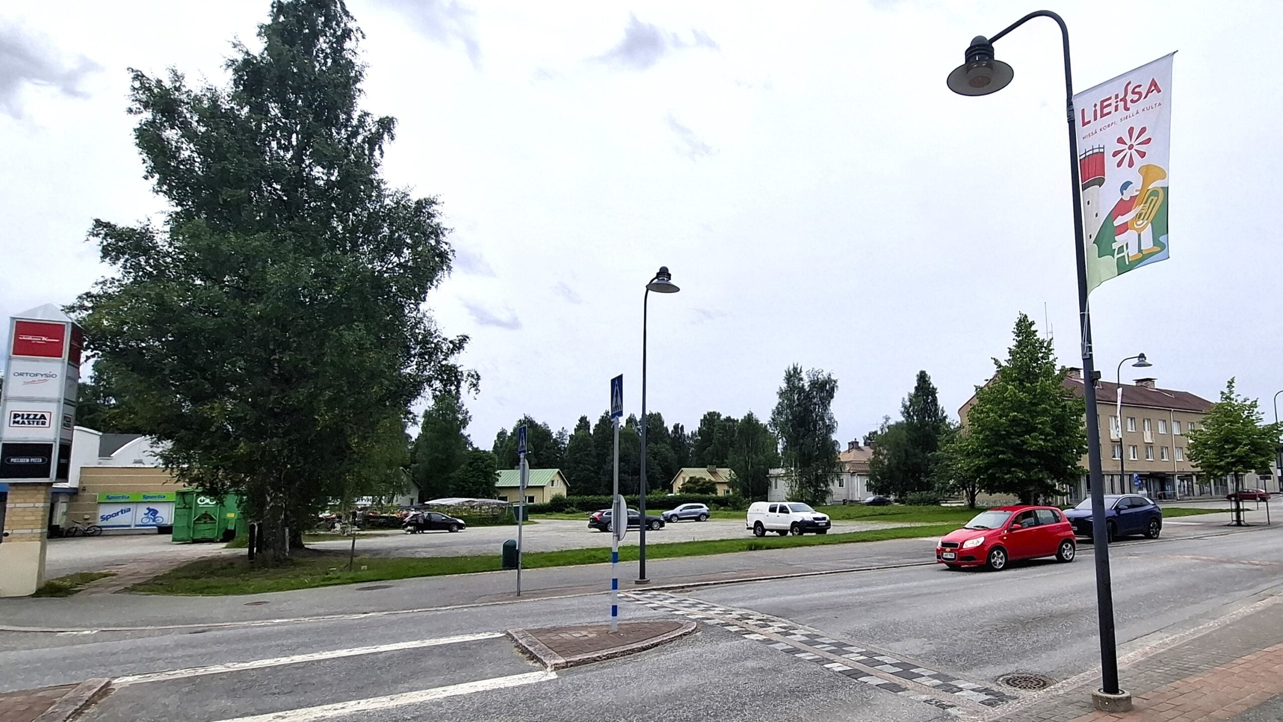 Lieksan uuden torin paikka kaupungin keskustassa. Kuvassa näkyy myös kaupunki viiri ja muutamia autoja parkkeerattuina.